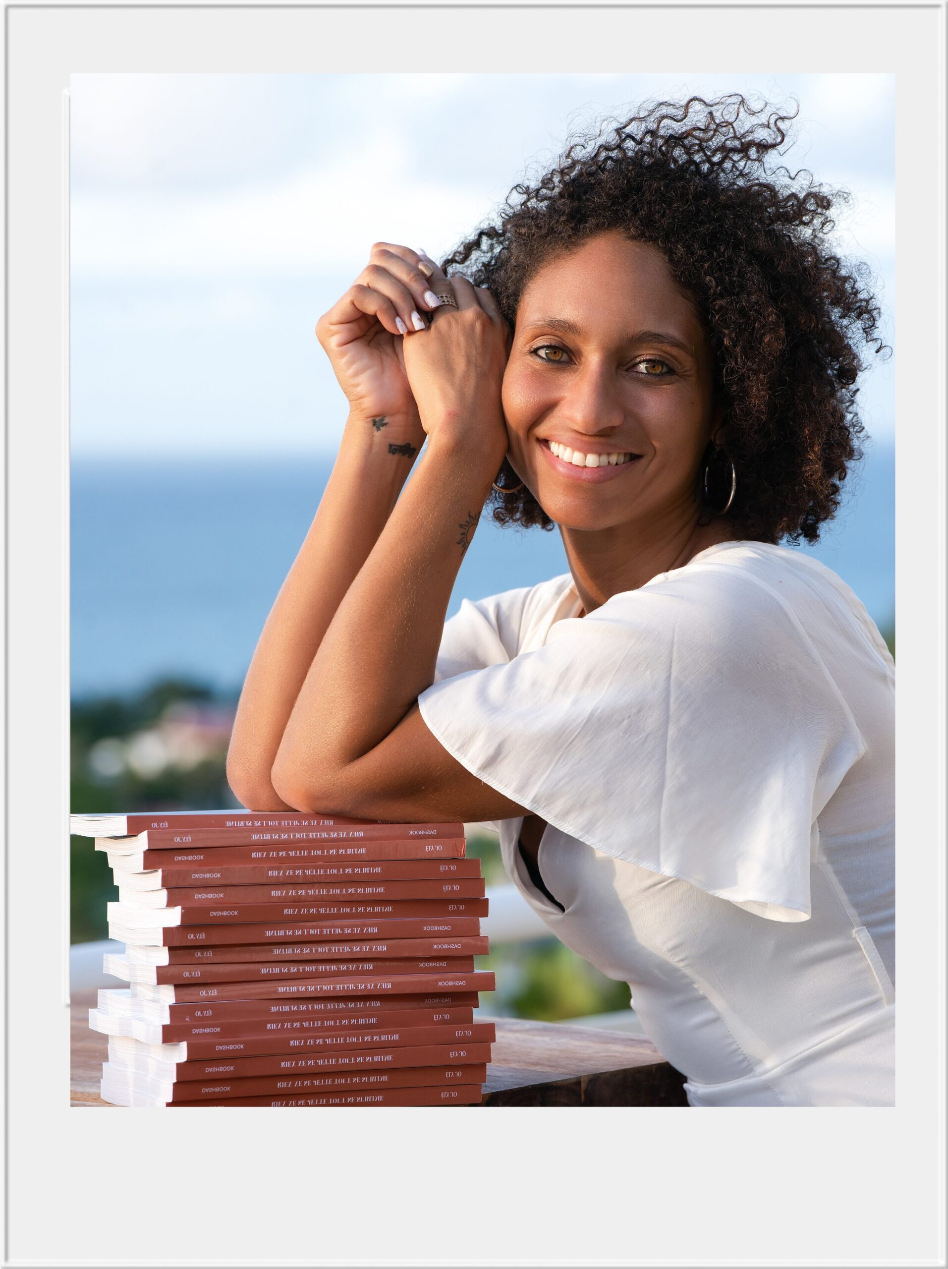 Femme souriante appuyée sur pile de livres dehors